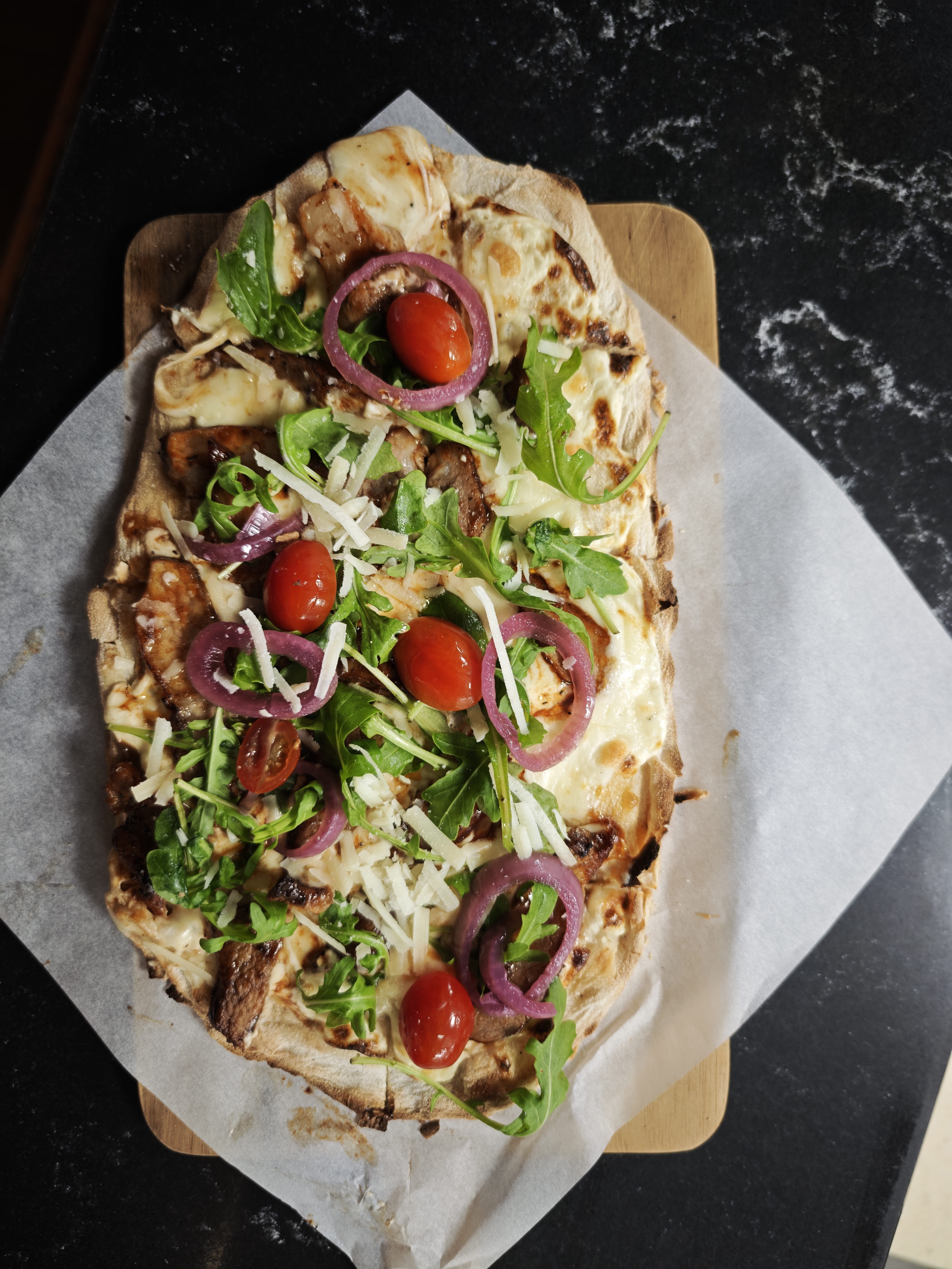 Pinsa Pluma med bianco bas, hickory grillad pluma, ruccola, picklad rödlök, coctail tomater toppad med parmesan.